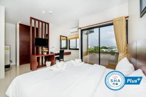 a bedroom with a large white bed and a desk at The Topaz Residence Phuket Town in Phuket Town