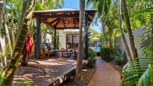 a wooden deck with a pergola in a backyard with palm trees at The Pearle of Cable Beach in Broome