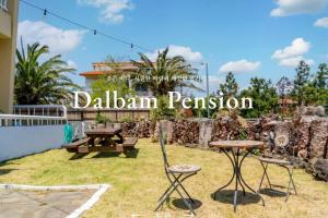 a garden with a table and chairs and a sign that reads dahlian permission at Jeju Dalbam Pension in Seogwipo