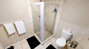 a white bathroom with a shower and a toilet at Gautrain Hatfield Lovely Studio in Pretoria