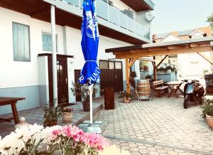 a blue umbrella on the patio of a house at Pension Seeblick Latzko in Neusiedl am See
