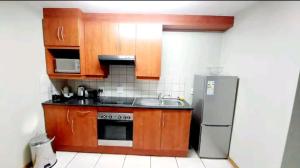 a kitchen with wooden cabinets and a stainless steel refrigerator at Gautrain Hatfield Lovely Studio in Pretoria