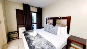 a bedroom with a large bed with blue and white pillows at Gautrain Hatfield Lovely Studio in Pretoria