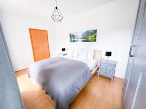 una camera bianca con letto e comodino di Idyllische Wohnung mit Garten! a Bad Gleichenberg
