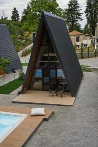 a triangular house with a table and chairs next to a pool at Pavliani4rest - Luxury Cabins in Pavliani