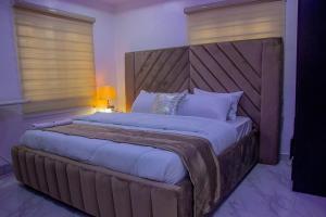 duże łóżko z dużym drewnianym zagłówkiem w sypialni w obiekcie Thistle Greens Apartment w mieście Ikeja