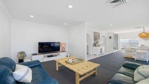a living room with a blue couch and a table at Hibbard Waterfront Escape in Port Macquarie