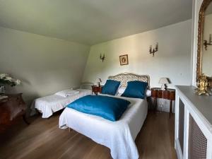 a bedroom with two beds with blue pillows at L’orangerie chambres d’hôtes in Motteville