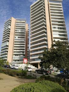 two tall buildings with cars parked in a parking lot at Exquisito y amplio departamento en el mejor sector de Reñaca in Concón