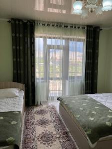 - une chambre avec un lit et une grande fenêtre dans l'établissement Гостевой дом RAZAM, à Bosteri