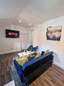 a living room with a blue couch and a table at Sandbach Apartments in Sandbach