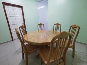 una mesa de madera y sillas en una habitación con puerta en DIY Palm Court 3BR Apartment, 7 Guests en Kuantan