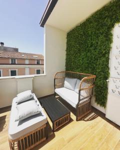 een balkon met 2 rieten stoelen en een groene muur bij Nontiscordardime in Orsogna