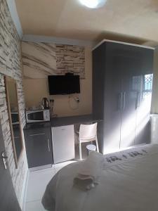 a bedroom with a bed and a kitchen with a microwave at LINGE'S LODGE EXTENSION in Lusikisiki
