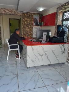 a man sitting at a counter with a computer at LINGE'S LODGE EXTENSION in Lusikisiki