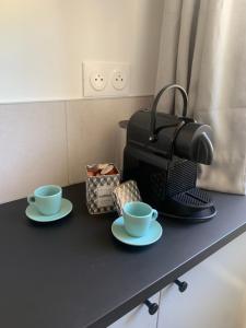 a table with two cups and a coffee maker at Le kocon, dans un écrin, le calme à la mer in Saint-Pair-sur-Mer