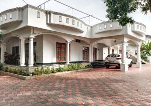 a white house with a car parked in front of it at Vaiga Homes - Vembanadu Lakeview Retreat in Cochin