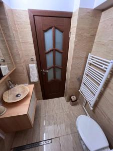 ein Bad mit einem WC, einem Waschbecken und einer Tür in der Unterkunft MNM Mitropolie in Iaşi