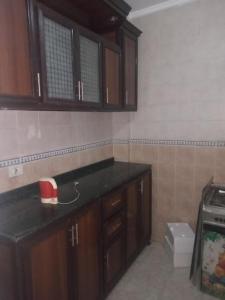 una cocina con armarios de madera y un aparato rojo en la encimera en Furnished apt for rent Have fun, en Madinaty