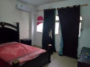 1 dormitorio con cama roja y cortinas azules en Furnished apt for rent Have fun, en Madinaty