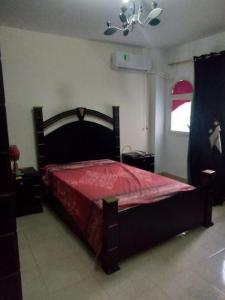 1 dormitorio con 1 cama grande con colcha roja en Furnished apt for rent Have fun, en Madinaty
