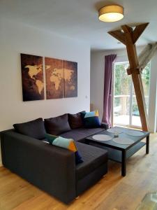 Ferienwohnung im Mittelpunkt في Nortorf: غرفة معيشة مع أريكة سوداء وطاولة زجاجية