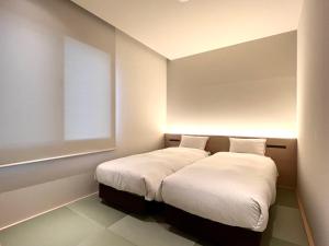 a bedroom with a bed with white sheets and a window at ABiz hotel in Kyoto