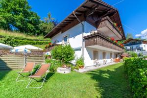 a house with two chairs in the yard at Pension Kofler in Vollan