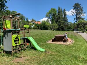 un enfant assis sur un banc à côté d'une aire de jeux dans l'établissement Appartement de standing à Vallorbe, à Vallorbe