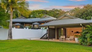 a house with a white fence and a yard at Cape Vue Byron in Byron Bay