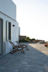 a row of benches sitting next to a building at Tholos Guest House in Sifnos