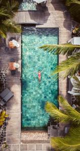 a person is standing in a swimming pool at Hôtel 20 Degrés Sud - Relais & Châteaux in Grand Baie