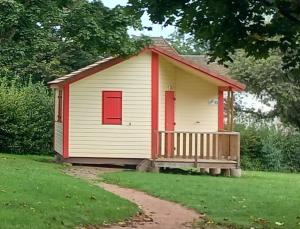 une petite maison blanche et rouge avec une terrasse couverte dans l'établissement Camping Les Feuilles Chauffailles, à Chauffailles