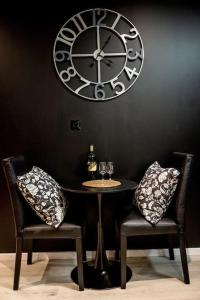 una mesa con dos sillas y un reloj grande en la pared en * Love Room jacuzzi *, en Aubie-et-Espessas