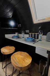a counter with two stools and plates and wine glasses at North Coast 500 Pods in Achmelvich