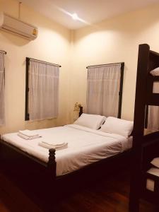 a bedroom with a bed with white sheets and a window at Thunyaporn Hostel in Trang
