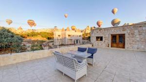 een patio met een tafel en stoelen en luchtballonnen bij Premium Cappadocia House in Goreme