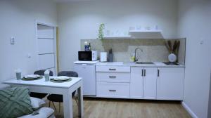 a kitchen with white cabinets and a table and a microwave at Apartament Royal in Dej