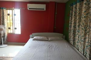Posto letto in camera con parete rossa. di OYO Nirmal Guest House a Guwahati