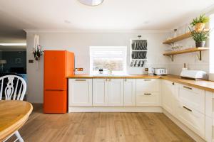 a kitchen with white cabinets and an orange refrigerator at Luxurious Complex: 2 barns together edge of Frome in Frome