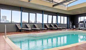 a large swimming pool with chairs and windows at 109 Simply Devine Hay St 2x2apt Poolgym in Perth