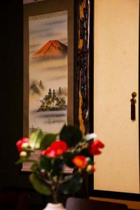 a plant with red flowers in a vase in front of a picture at 飛騨高山 八軒町戸建 in Takayama