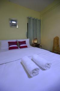 Un dormitorio con una cama blanca con toallas. en OYO 75440 Nara Hostel en Bangkok