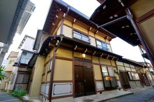 a yellow building with a balcony on a street at 飛騨高山 八軒町戸建 in Takayama