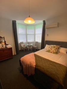 a bedroom with a bed and a table and a window at Turret House in Featherston
