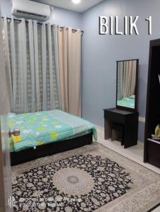 a bedroom with a bed and a mirror and a rug at Aisyah Homestay Kuantan - Jaya Gading in Kampong Seri Permatang Gading
