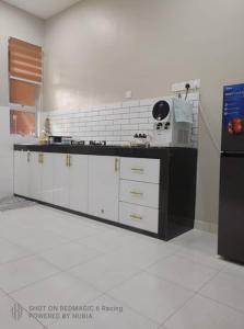 a kitchen with white cabinets and a black refrigerator at Aisyah Homestay Kuantan - Jaya Gading in Kampong Seri Permatang Gading