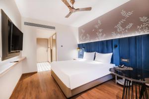 a bedroom with a large white bed and a table at 7 Apple Hotel Jal Mahal, Jaipur in Jaipur