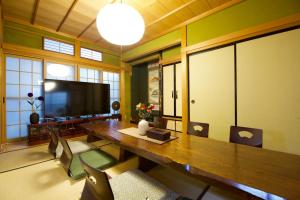 a dining room with a large wooden table and a flat screen tv at 飛騨高山 八軒町戸建 in Takayama