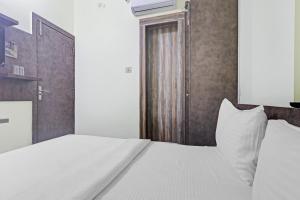 a bedroom with a white bed and a wooden door at Collection O Hotel Dhruv Tara Inn in Patna